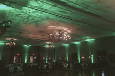 Dramatic green uplighting and marble-patterned ceiling projection in a reception space