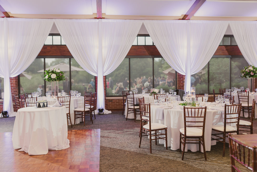 A room with tables and chairs, enhanced by drapings to create a clean look and soften the space.