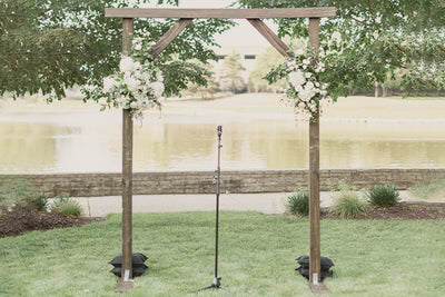 A timber wedding arch adorned with delicate flowers, creating a picturesque backdrop for the solemn ceremony.