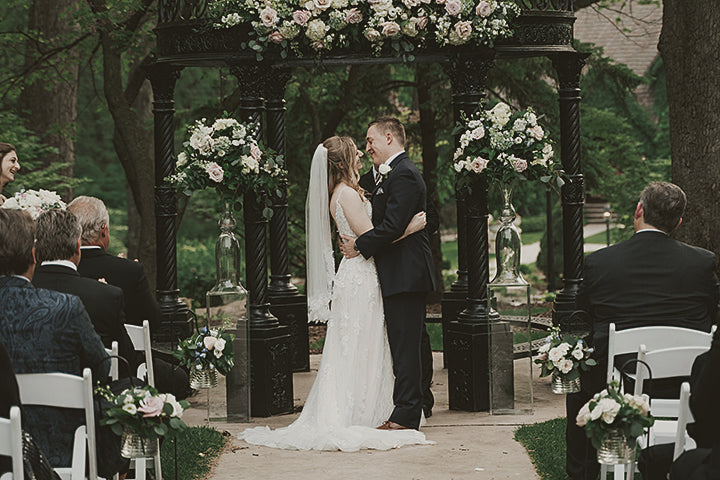 The personalized ceremony soundtrack sets the romantic mood as the bride and groom share a tender kiss in front of a gazebo.