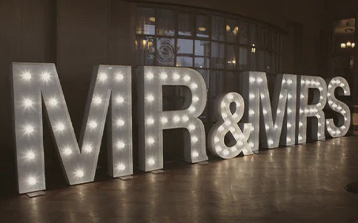 The word "Mr. and Mrs." is lit up with lights, creating a beautiful custom marquee sign.